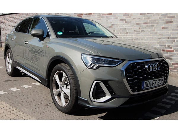Graugrüner Audi Q3 Sportback der Fahrschule Kaiser mit Beklebung an der Fahrerseite, vor einer Klinkerwand, Kennzeichen DO FK 206