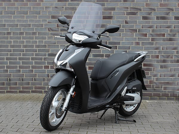 Schwarzer Honda-Roller der Fahrschule Kaiser mit Windschutzscheibe, vor einer Klinkerwand