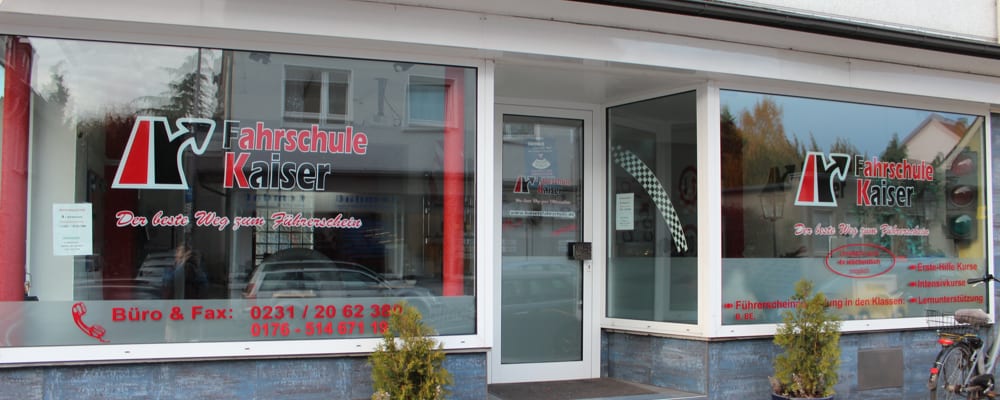 Schaufenster einer Filiale der Fahrschule Kaiser: das Logo als weiße Folienbeklebung auf der Scheibe, darunter die Telefonnummern